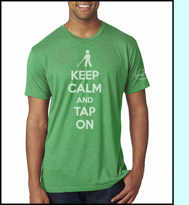Photo shows a soft green T-shirt with a sillouette of a cane user saying 'Keep Calm and Tap On'